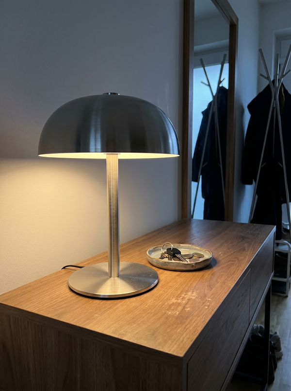 Brushed steel dome lamp lit on a hallway console with a key dish — Dalfa CH/FR