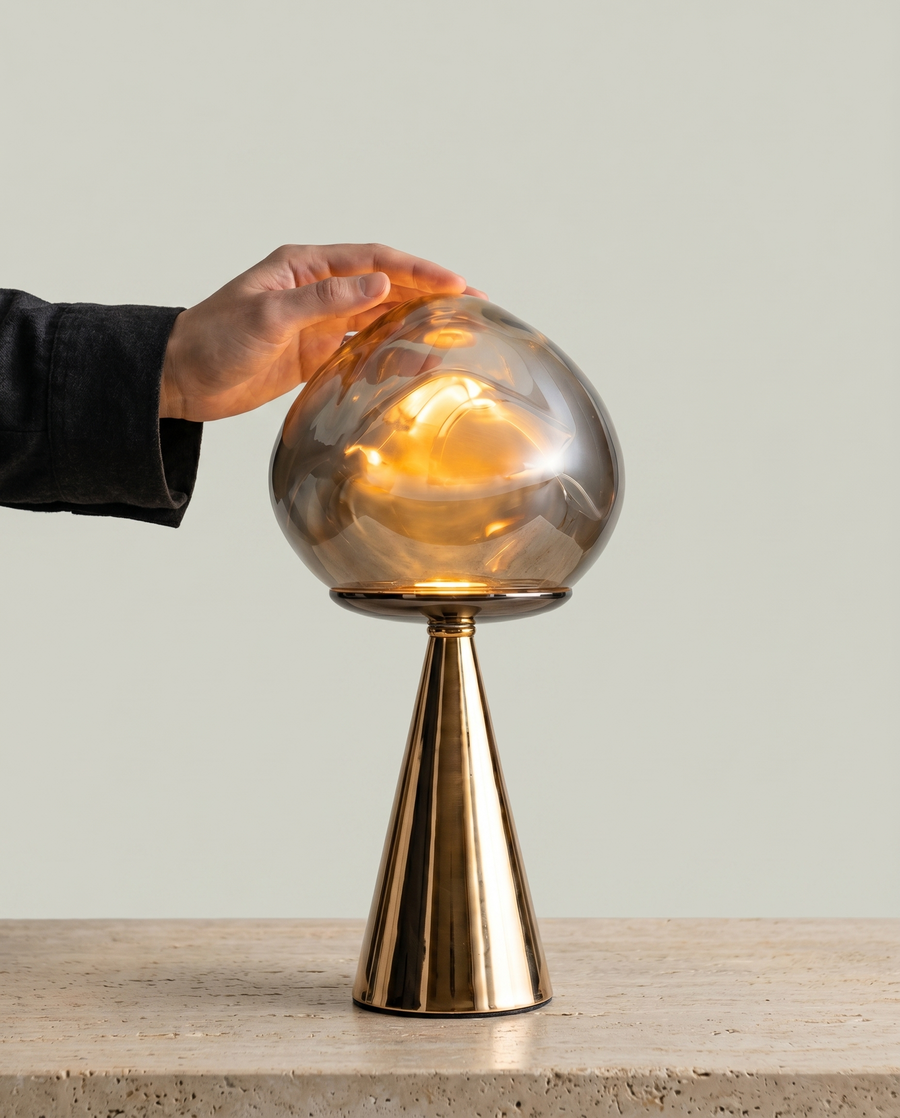 Mushroom Fumé smoked blown-glass globe lamp, golden cone base, dimmer 2700K — in use, hand on touch control | Dalfa CH/FR