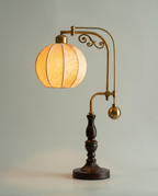 Botanical Arm brass swing-arm lamp, botanical fabric globe, dark wood base, 58 cm — lit hero shot | Dalfa CH/FR