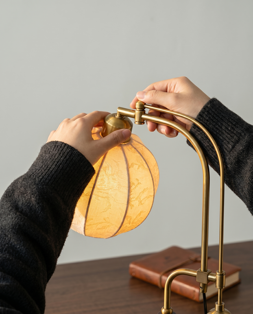 Botanical Arm brass swing-arm lamp, botanical fabric globe, dark wood base, 58 cm — in use, hand on touch control | Dalfa CH/FR