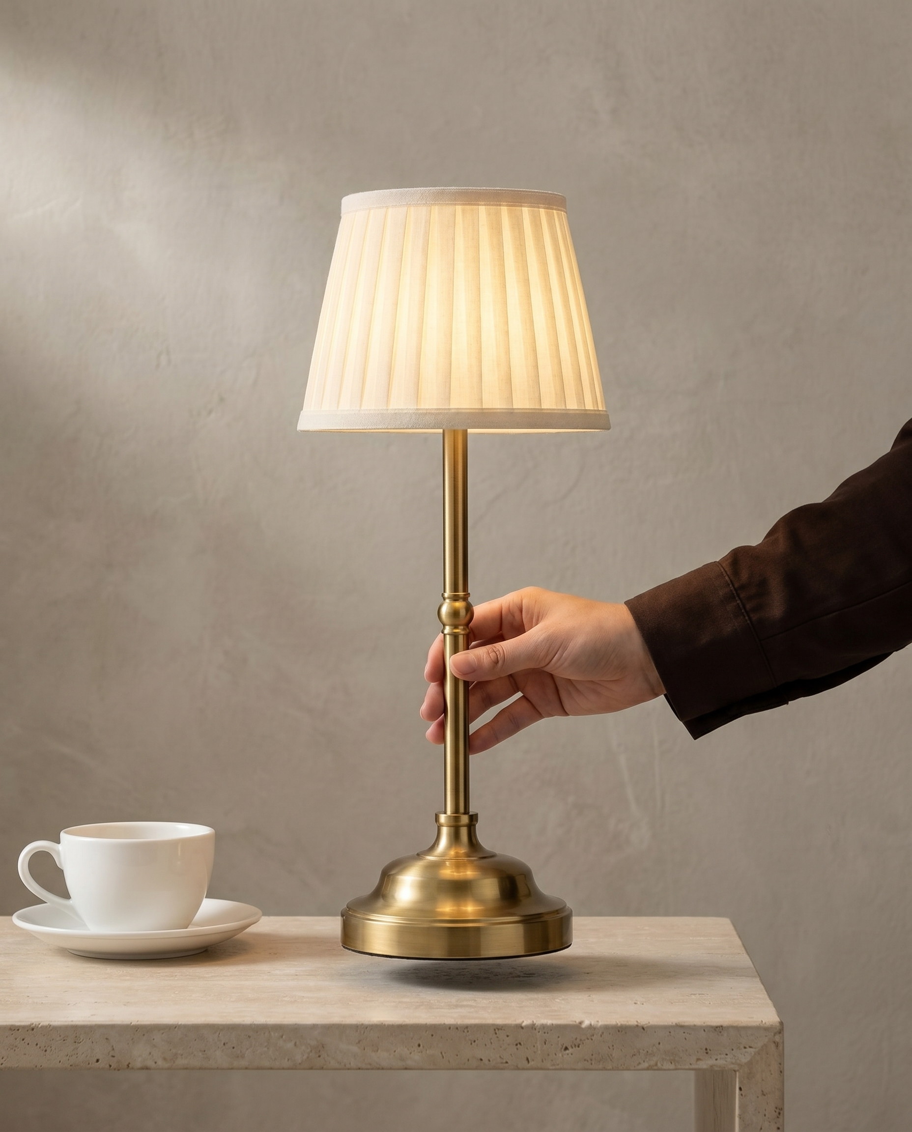 Pleated Brass cordless lamp, brass stem, pleated shade, USB-C dimmer, 40 cm — in use, hand on the brass stem | Dalfa CH/FR