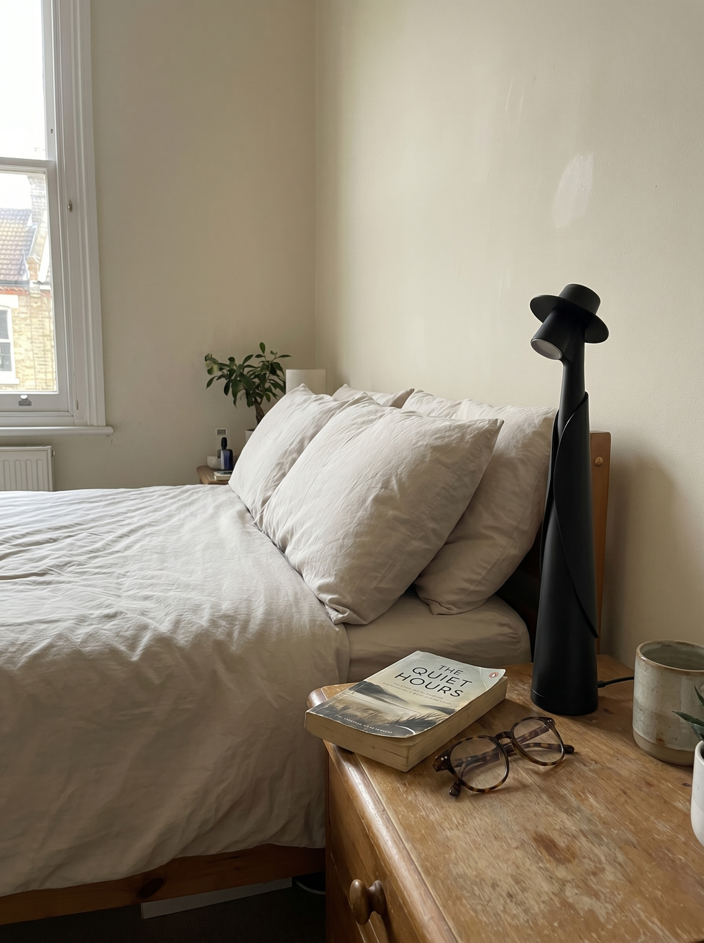 Matte black figure lamp on a bedside table with a book and glasses, real bedroom — Dalfa CH/FR
